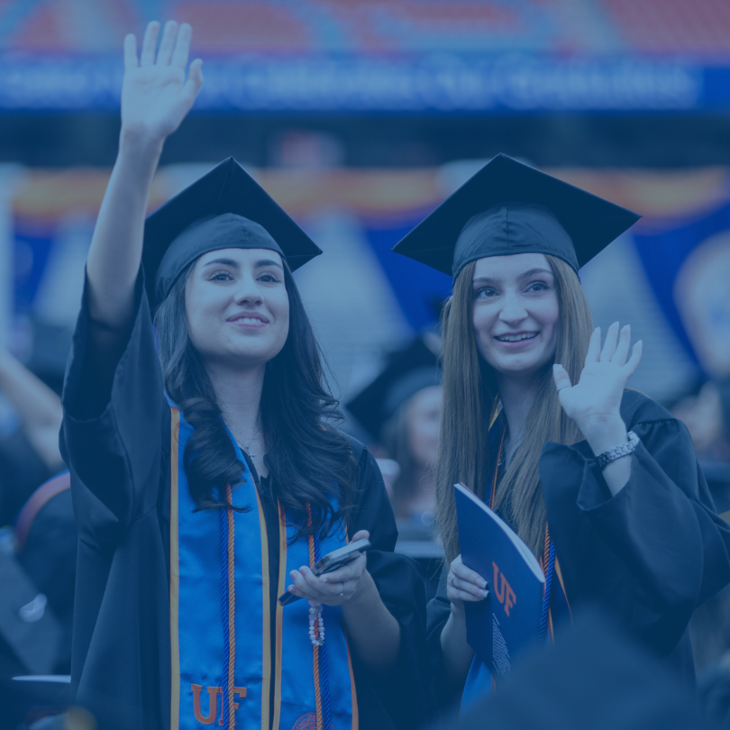 Two students waving at commencement.
